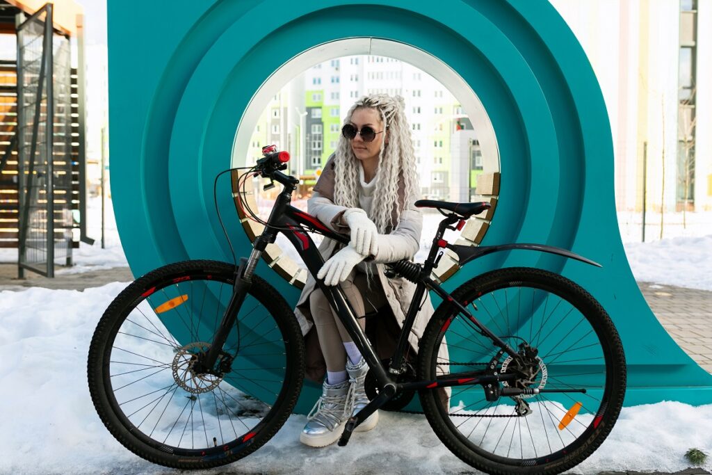 Kobieta opiera się o rower elektryczny - nie poci się, może elegancko się ubrać